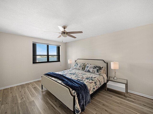 bedroom featuring a ceiling fan, visible vents, a textured ceiling, and wood finished floors