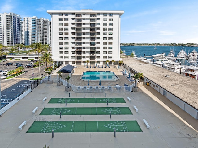 view of building exterior with a water view, fence, and a community pool