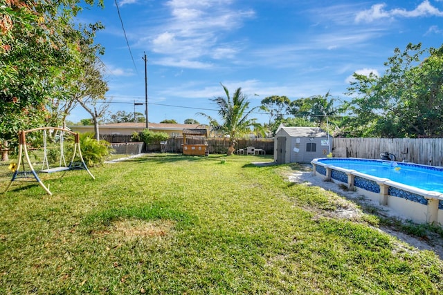 view of yard featuring a fenced in pool and a storage unit