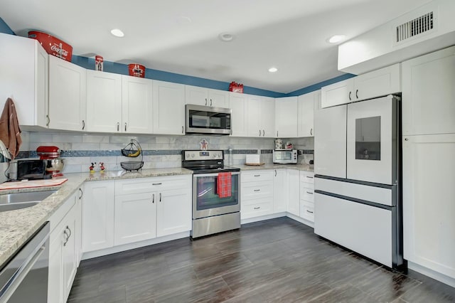 kitchen with decorative backsplash, white cabinetry, and appliances with stainless steel finishes