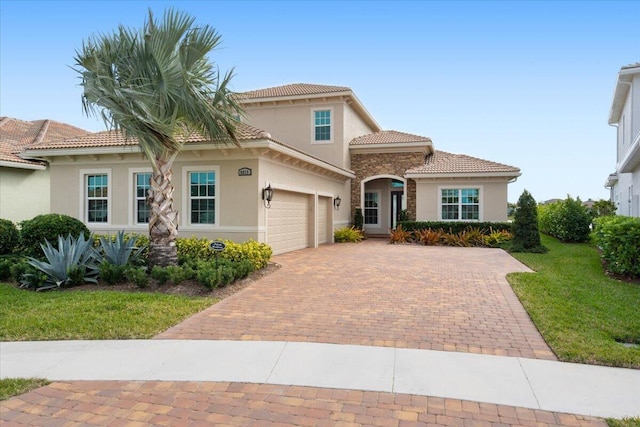 mediterranean / spanish-style home with a garage and a front lawn