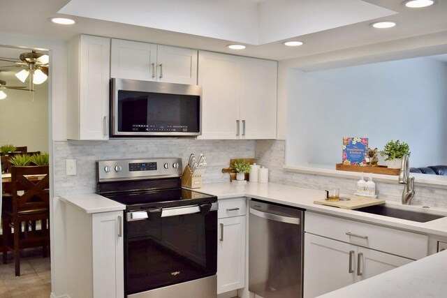 kitchen featuring stainless steel appliances, white cabinets, a sink, a peninsula, and a kitchen breakfast bar