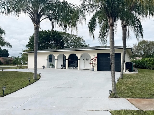 view of front facade featuring a garage, concrete driveway, a front lawn, and stucco siding