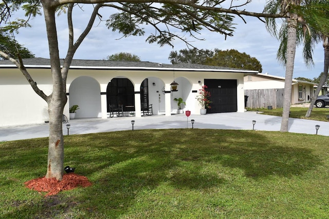 view of front facade featuring an attached garage, driveway, a front lawn, and stucco siding