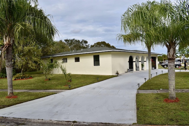 view of front facade featuring driveway, a front yard, and stucco siding