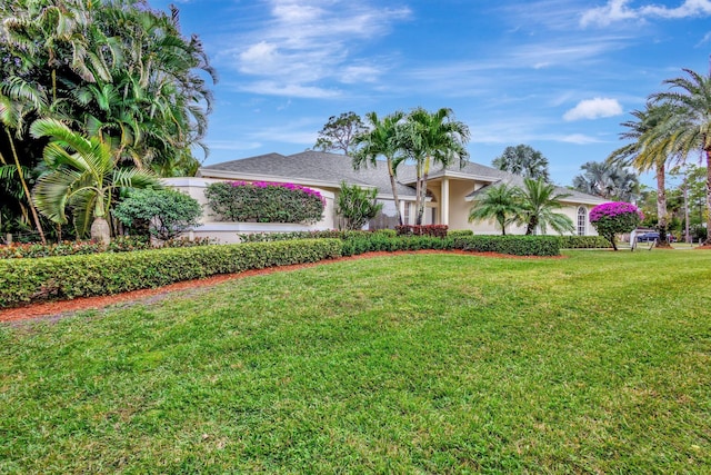 view of front of house featuring a front lawn, an attached garage, and stucco siding