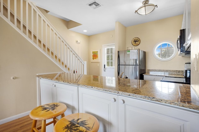 kitchen with white cabinets, stainless steel appliances, visible vents, and a healthy amount of sunlight