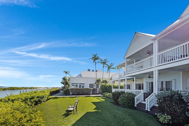 view of yard featuring a water view, a balcony, and a ceiling fan