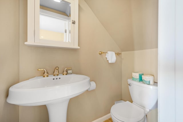 bathroom with lofted ceiling, baseboards, toilet, and a sink