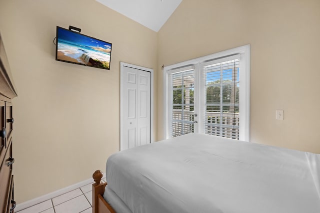 bedroom with lofted ceiling, a closet, light tile patterned flooring, and baseboards