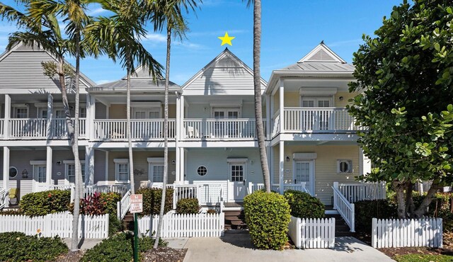 view of front of property with a standing seam roof, metal roof, a porch, and a fenced front yard