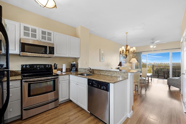 kitchen featuring light wood finished floors, a peninsula, appliances with stainless steel finishes, and a sink