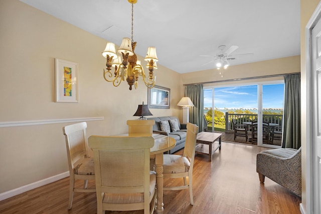 dining room featuring ceiling fan with notable chandelier, baseboards, and wood finished floors