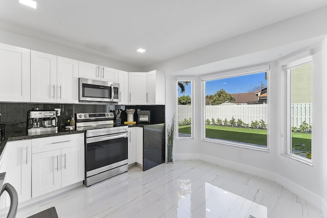 kitchen featuring decorative backsplash, stainless steel appliances, and white cabinets