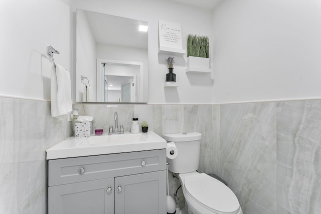 bathroom featuring vanity, tile walls, and toilet