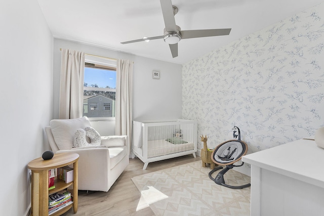 bedroom with ceiling fan, light hardwood / wood-style flooring, and a crib