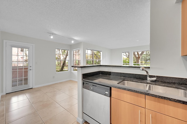 kitchen featuring dark stone counters, a textured ceiling, sink, dishwasher, and light tile patterned flooring