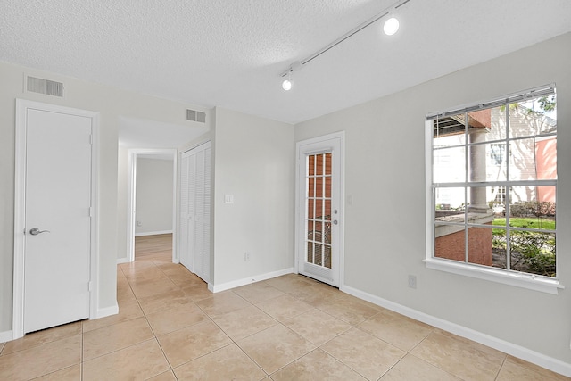 tiled empty room with a textured ceiling and rail lighting