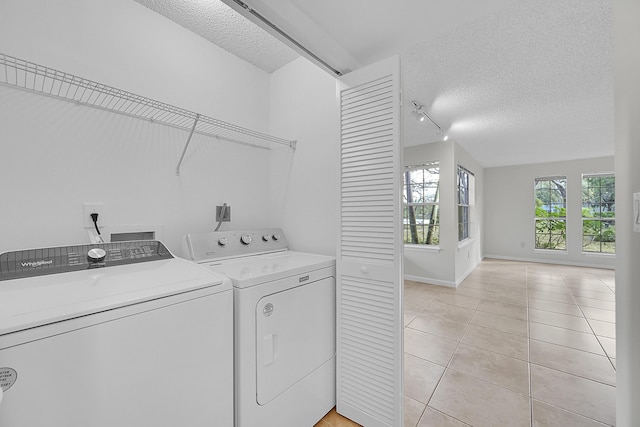 washroom with washing machine and dryer, light tile patterned floors, a textured ceiling, and track lighting