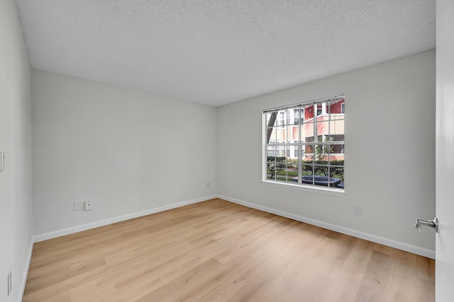 spare room featuring a textured ceiling and light hardwood / wood-style flooring