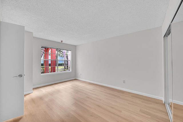 unfurnished room featuring light hardwood / wood-style floors and a textured ceiling