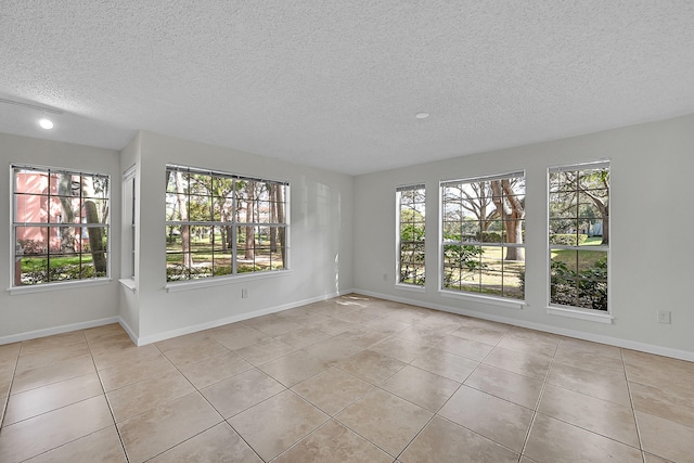 spare room featuring a textured ceiling, a wealth of natural light, and light tile patterned flooring