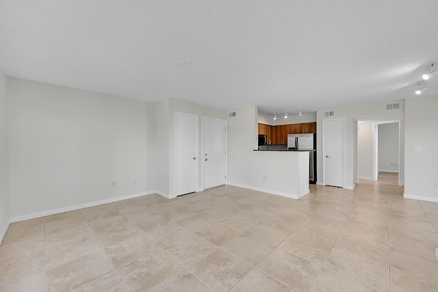 unfurnished living room featuring light tile patterned floors, a textured ceiling, and track lighting