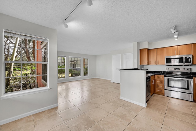 kitchen with light tile patterned flooring, track lighting, and appliances with stainless steel finishes