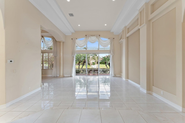 unfurnished room with light tile patterned floors, decorative columns, and crown molding