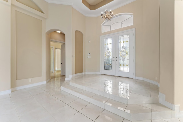 foyer featuring french doors, a high ceiling, crown molding, a chandelier, and light tile patterned floors