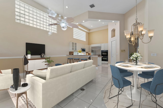 living room featuring light tile patterned flooring, a high ceiling, and ceiling fan with notable chandelier