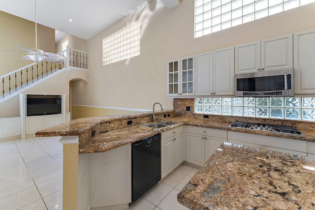 kitchen featuring sink, a towering ceiling, decorative backsplash, white cabinets, and appliances with stainless steel finishes