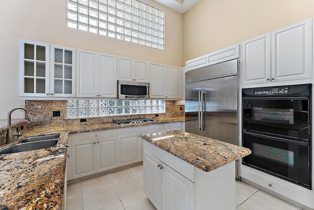 kitchen with white cabinets, sink, appliances with stainless steel finishes, and a high ceiling