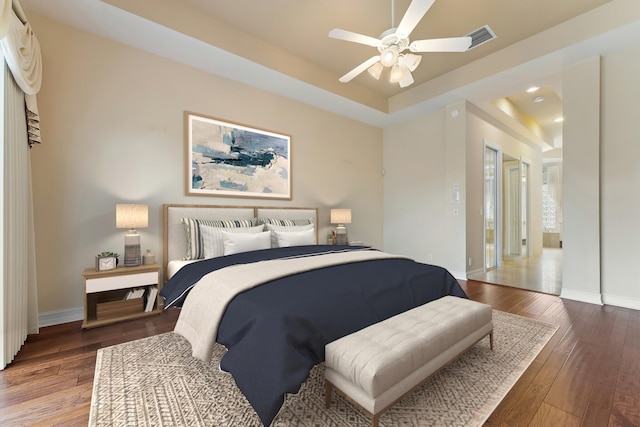 bedroom featuring wood-type flooring, a tray ceiling, and ceiling fan