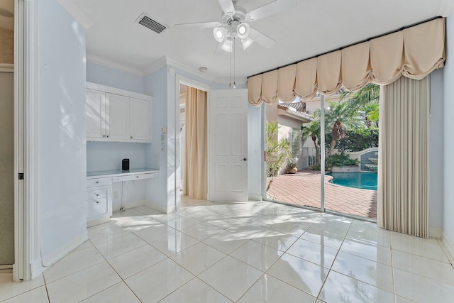 unfurnished dining area with crown molding, ceiling fan, built in desk, and light tile patterned floors