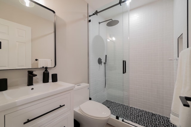 bathroom featuring vanity, a shower with shower door, and toilet