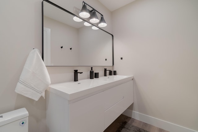 bathroom with hardwood / wood-style floors, vanity, and toilet