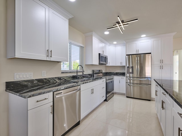 kitchen featuring light tile patterned floors, white cabinets, dark stone counters, appliances with stainless steel finishes, and sink