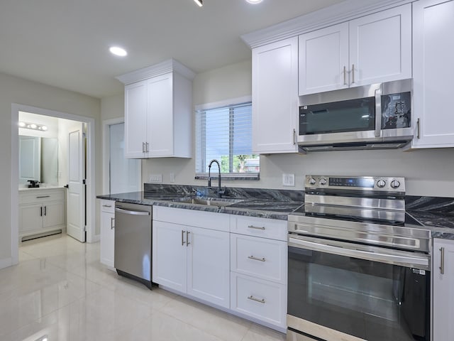 kitchen with white cabinets, dark stone counters, appliances with stainless steel finishes, and sink