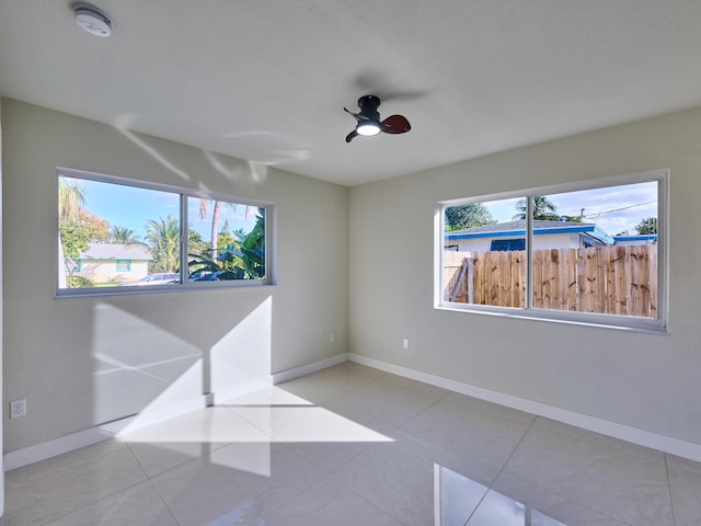 tiled empty room with ceiling fan and a wealth of natural light