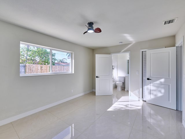 bedroom with light tile patterned floors, connected bathroom, and ceiling fan