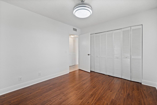 unfurnished bedroom with dark hardwood / wood-style flooring and a closet