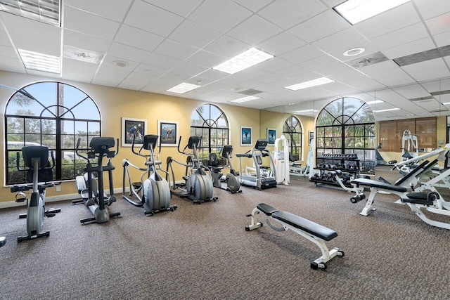 gym featuring a drop ceiling and a healthy amount of sunlight