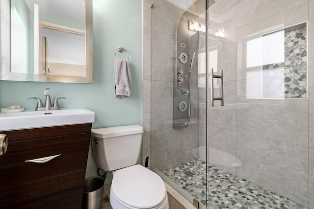 bathroom with toilet, vanity, and a shower with shower door