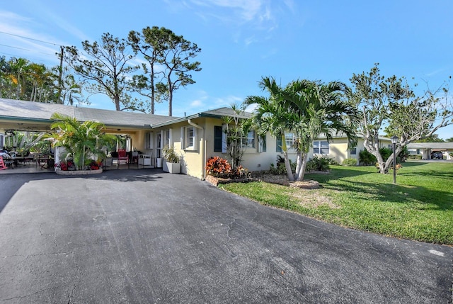 ranch-style home featuring a front lawn and a carport