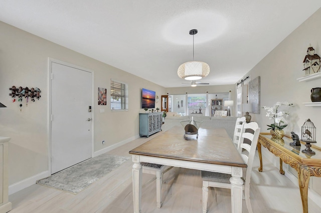 dining area with a barn door and light wood-type flooring