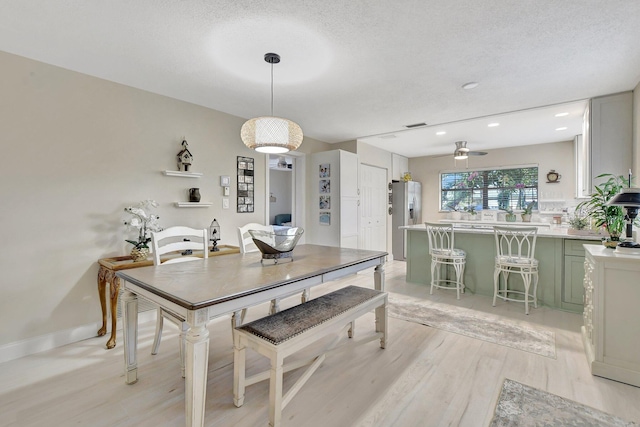 dining area with a textured ceiling, light hardwood / wood-style floors, and ceiling fan