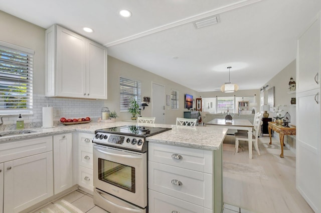 kitchen with white cabinets, electric stove, sink, a healthy amount of sunlight, and kitchen peninsula