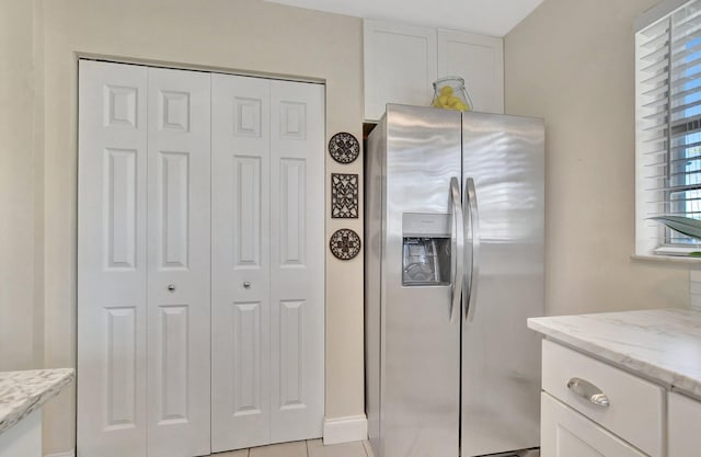 kitchen featuring white cabinets, stainless steel fridge, and light stone counters