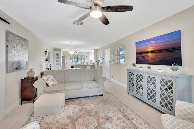 living room with light hardwood / wood-style flooring and ceiling fan